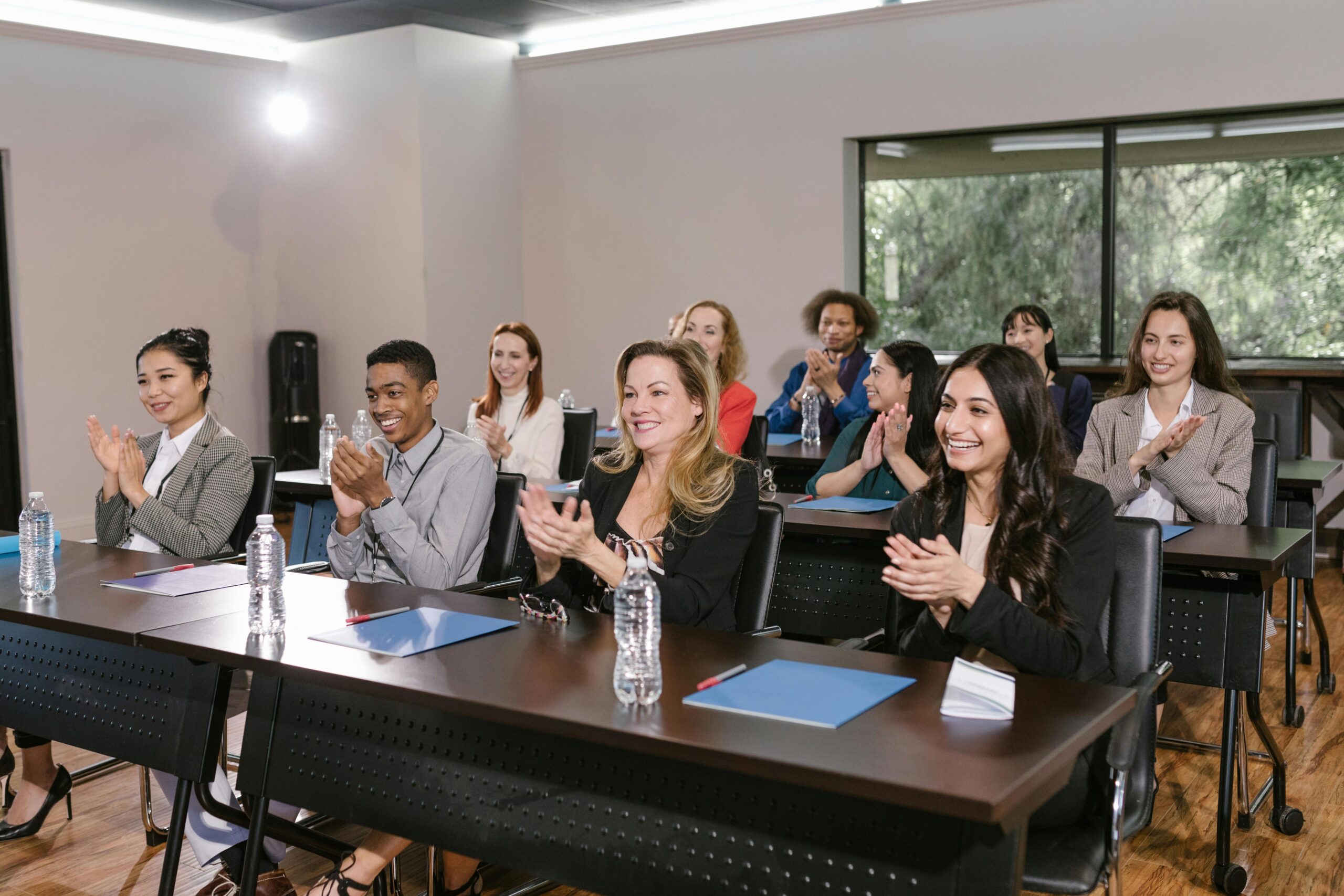 Home A diverse group of adults applauding in a business seminar setting.